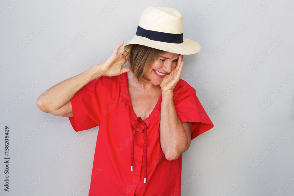 older woman laughing with hat against gray wall older woman laughing with hat against gray wall