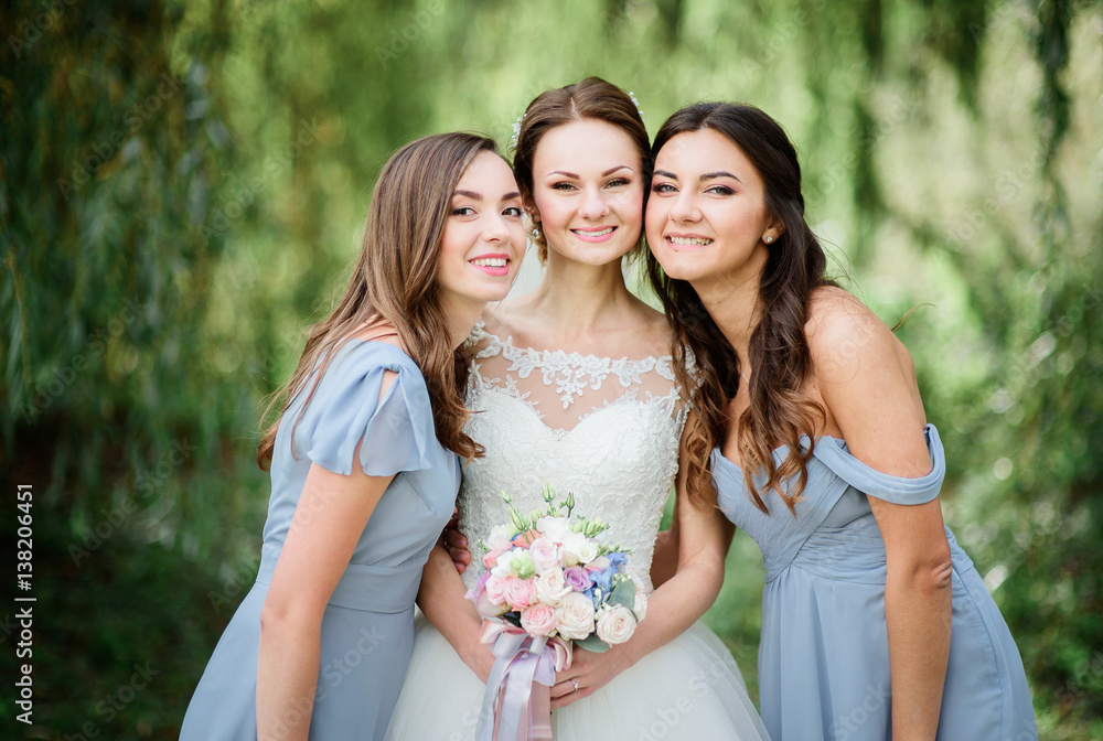 Bridesmaids in blue dresses surround pretty bride on green lawn Bridesmaids in blue dresses surround pretty bride on green lawn