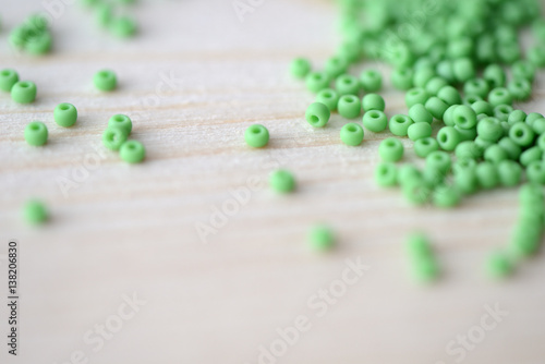 Scattered seed beads of light green color on a wooden background