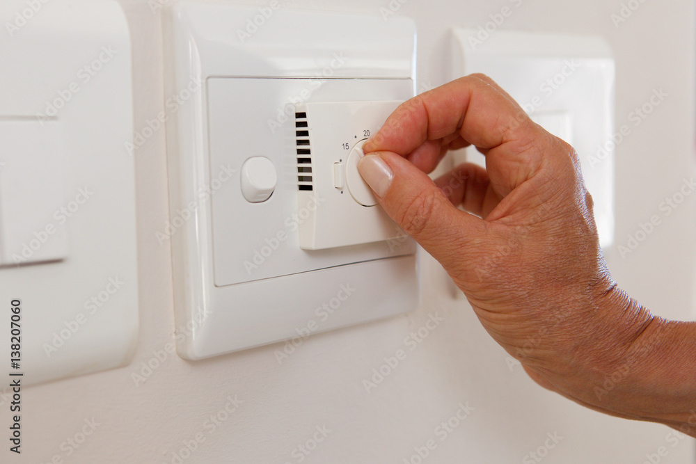 woman hand adjusting temperature on dial woman hand adjusting temperature on dial
