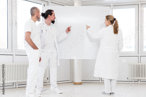 Drei Ärzte stehen vor einer weißen Tafel, Textfreiraum