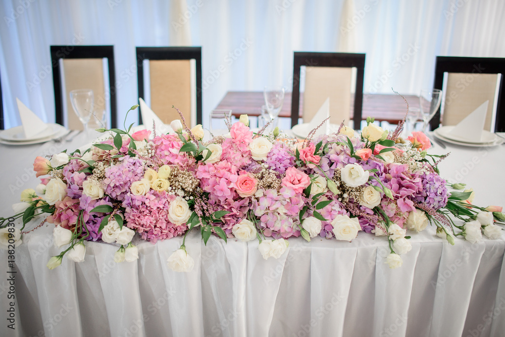 Obraz premium Garland made of pink roses and hydrangeas lies on white dinner table