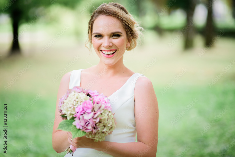 Bride smiles broad holding bouquet of hydrangeas Bride smiles broad holding bouquet of hydrangeas
