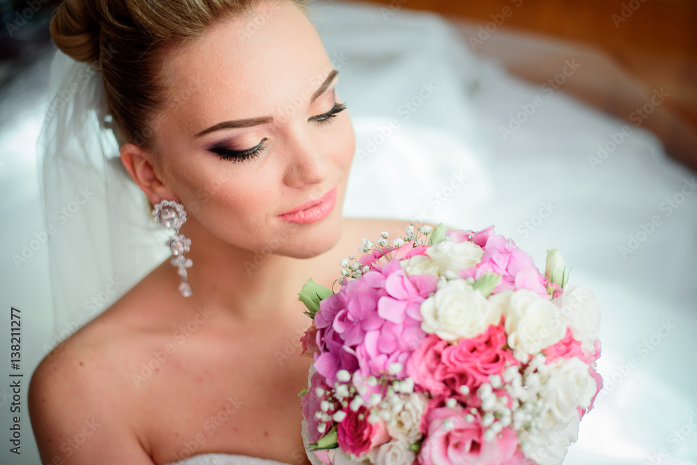 Stunning blonde bride sits on the floor with pink bouquet in her arms Stunning blonde bride sits on the floor with pink bouquet in her arms