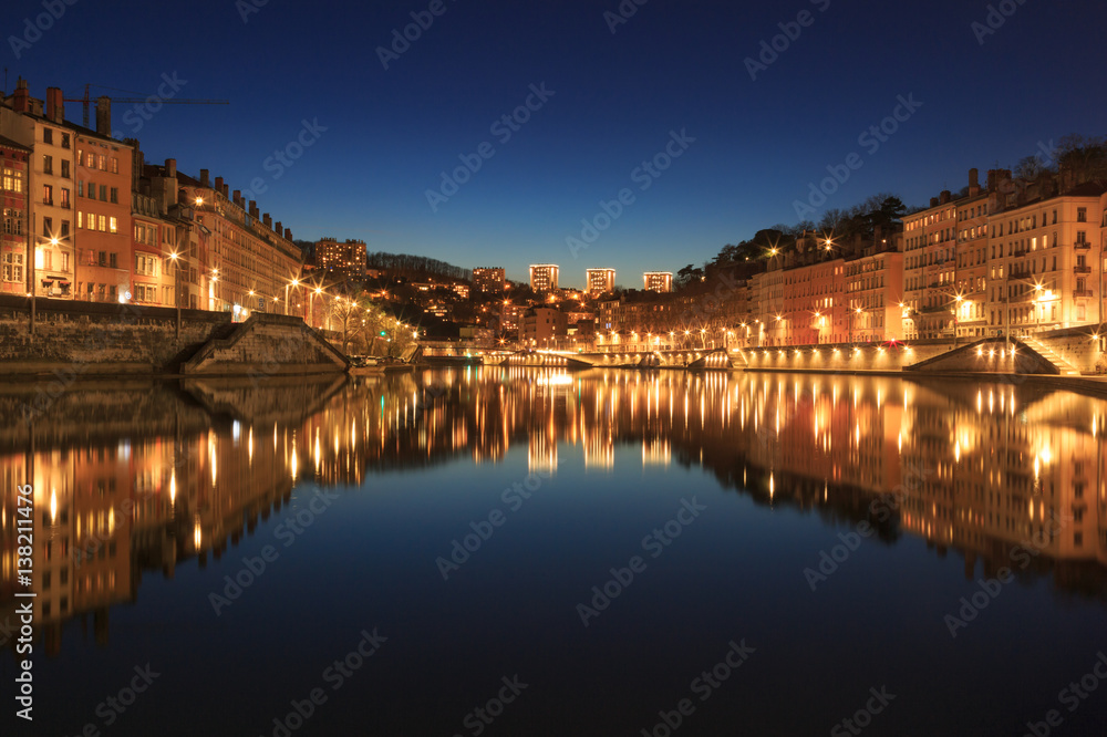 Illuminated Vieux Lyon reflected in the Saone river during a tranquil evening in Lyomn, France.