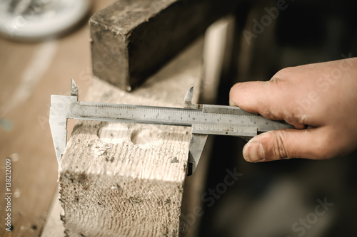 Carpenter using ruler for his job in carpentry workshop