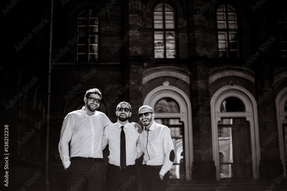Black and white picture of groom and groomsmen without jackets but in black sunglasses