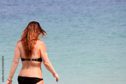 European tourists girl in a bikini on the beach with ocean background. 