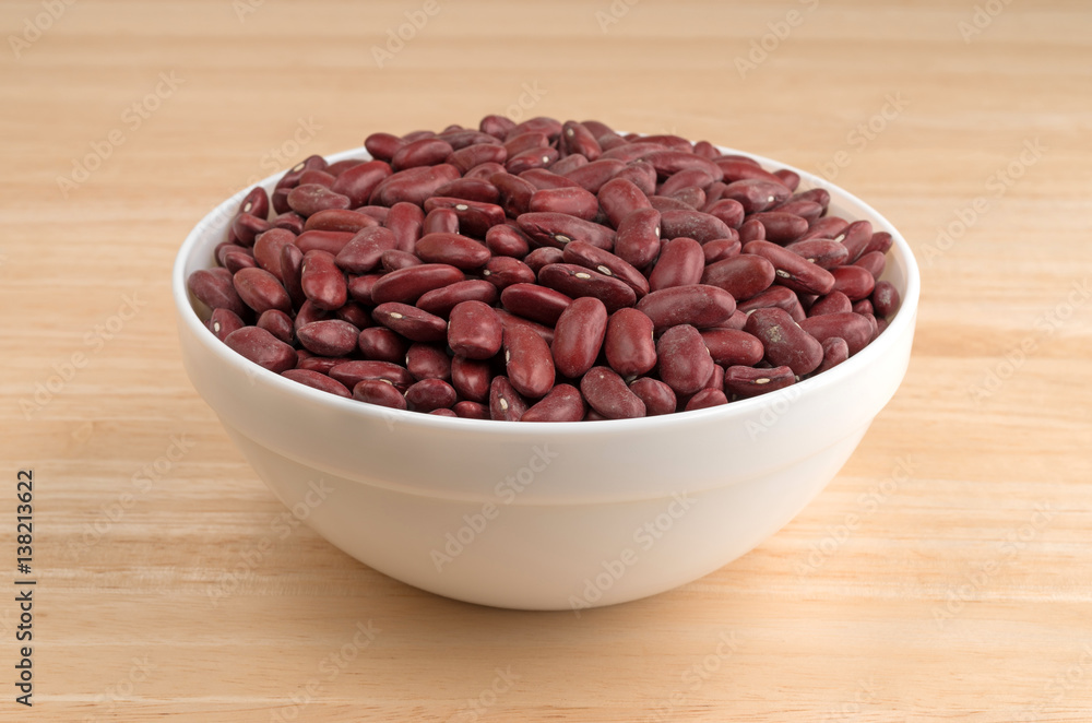 Bowl filled with dark red organic kidney beans atop a wood table. Bowl filled with dark red organic kidney beans atop a wood table.