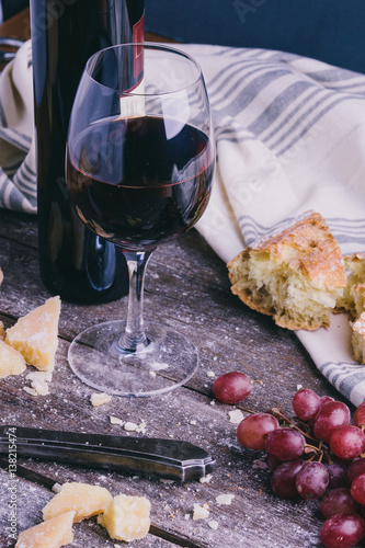 Red wine with grapes bread cheese on wooden table