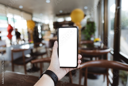 Close up hands holding cell telephone with blank copy space screen for your advertising text message or promotional content, in coffee shop, in selective focus.