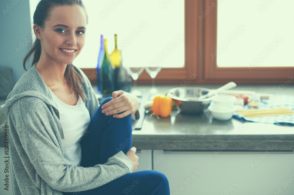 Young woman sitting a table in the kitchen . Young woman sitting a table in the kitchen .