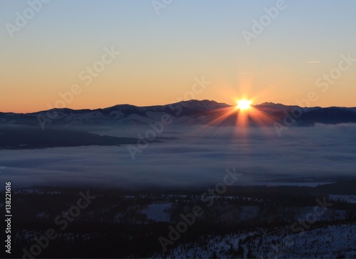 Sunset over mountains with fog.