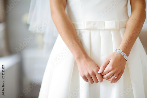 Bride's hands on beautiful white wedding dress