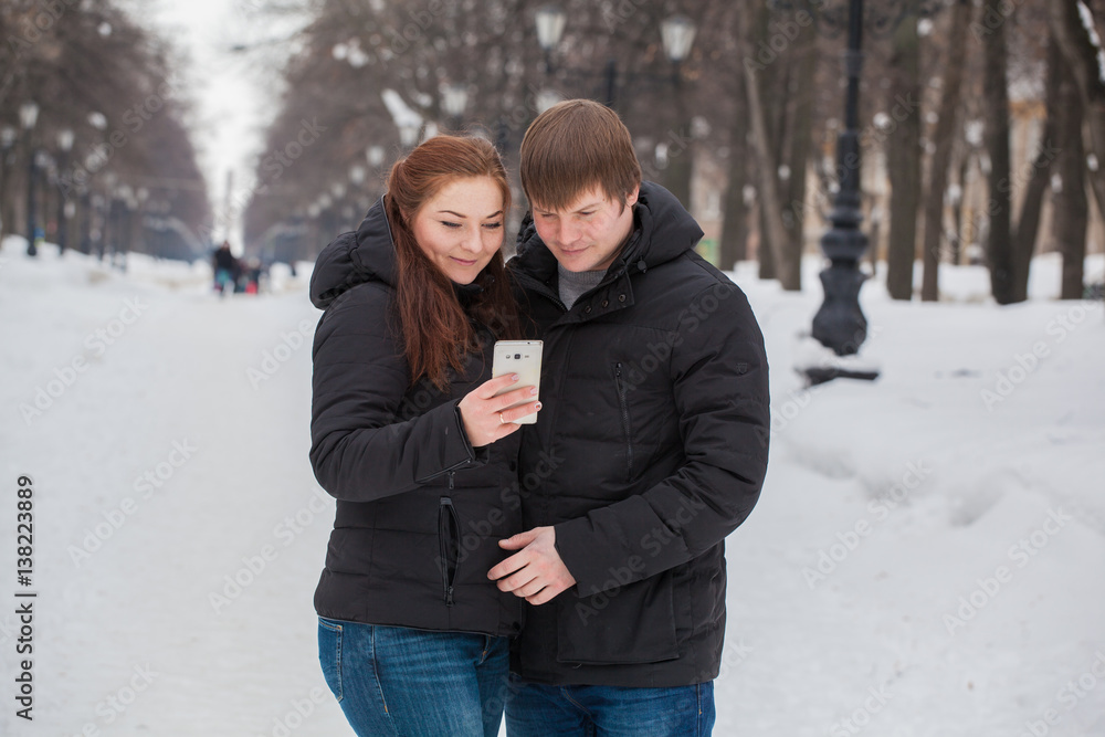 man and woman on a winter outing to the gadget in his hands man and woman on a winter outing to the gadget in his hands