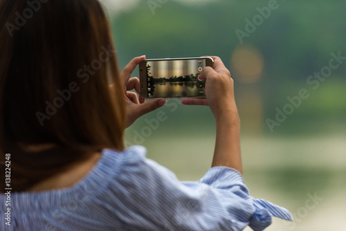Women are using a smartphone camera take photo at Hoan Kiem Lake in Ha Noi, Vietnam