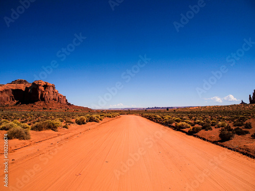 Desert sand road trough Monument Valley with clear blue sky  Utah  USA