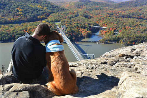 Obraz na plátně A young man and his twelve-year-old golden retriever taking a moment to admire the beautiful view overlooking the Hudson River Valley