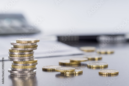 Euromünzen, Stift und Taschenrechner auf spiegelder Tischplatte photo