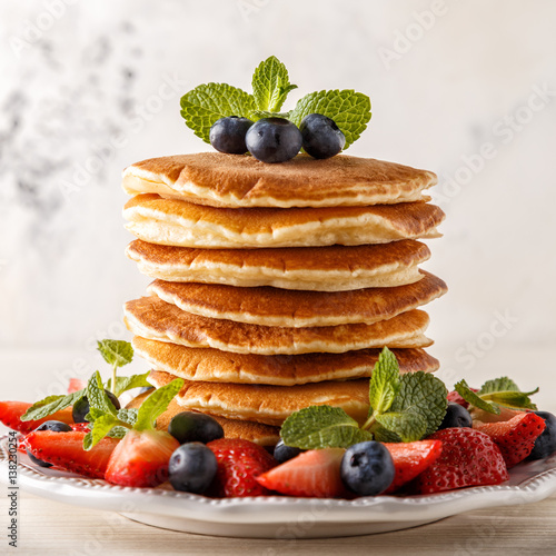 Homemade pancakes with berries and fruit on a white background.