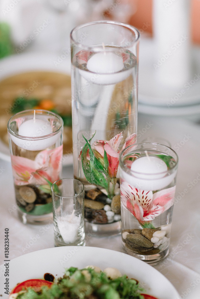 flowers and round candles floating in a glass of water flowers and round candles floating in a glass of water