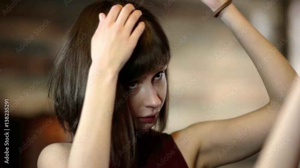 Young woman looking in the mirror brushing her hair Young woman looking in the mirror brushing her hair
