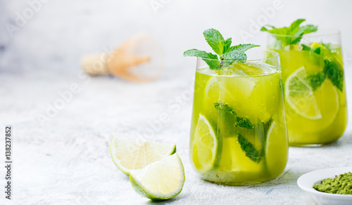 Matcha iced green tea with lime and fresh mint on a marble background. Copy space