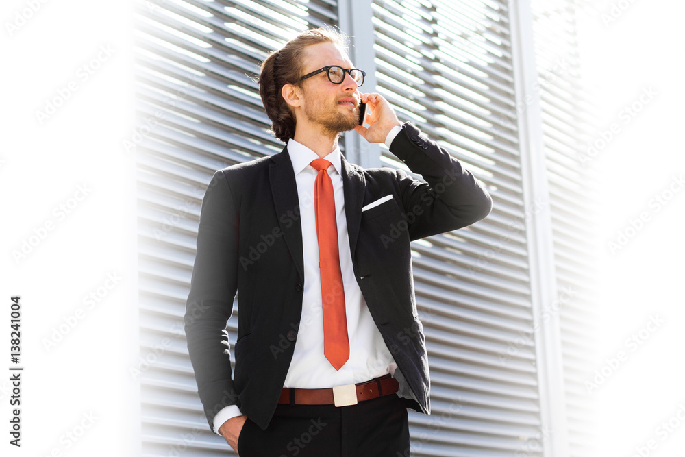 A businessman with a beard and glasses talking on the phone. Space for text. A businessman with a beard and glasses talking on the phone. Space for text.