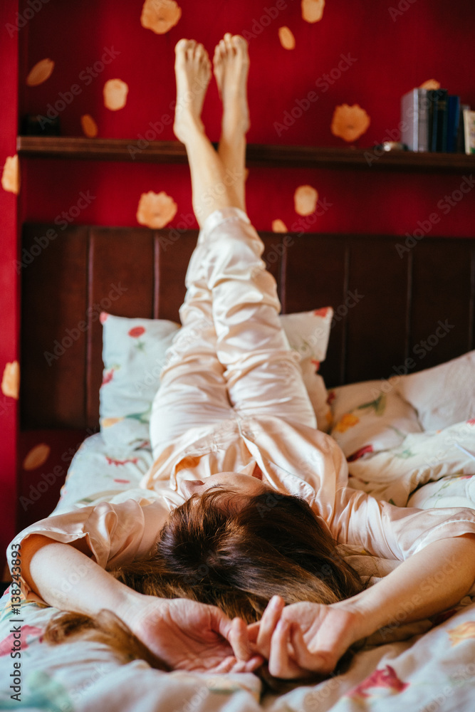 Φωτογραφία Vertical portrait of charming young woman in sleepwear relaxing with her feet up in the bed