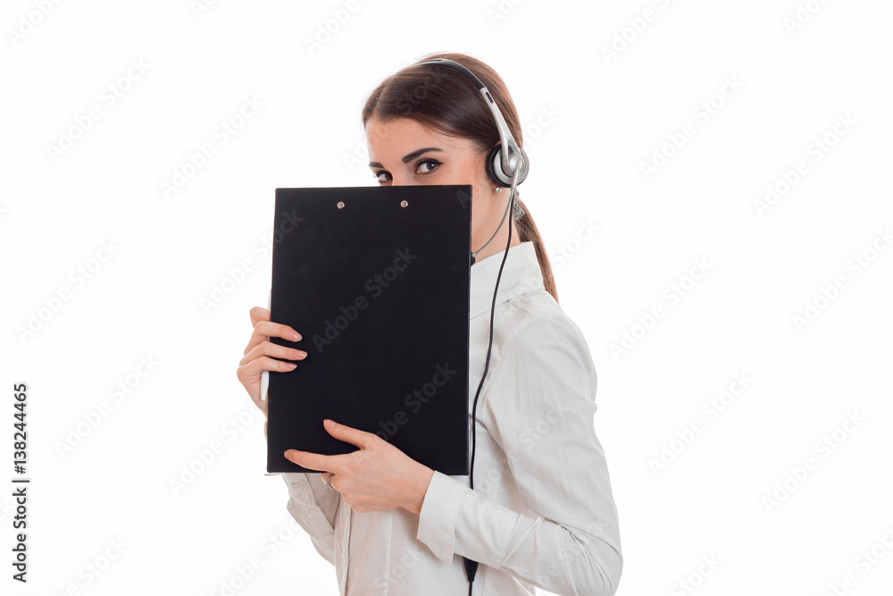 cute brunette woman working in call center with headphones and microphone hide her smile behind a blackboard isolated on white background cute brunette woman working in call center with headphones and microphone hide her smile behind a blackboard isolated on white background