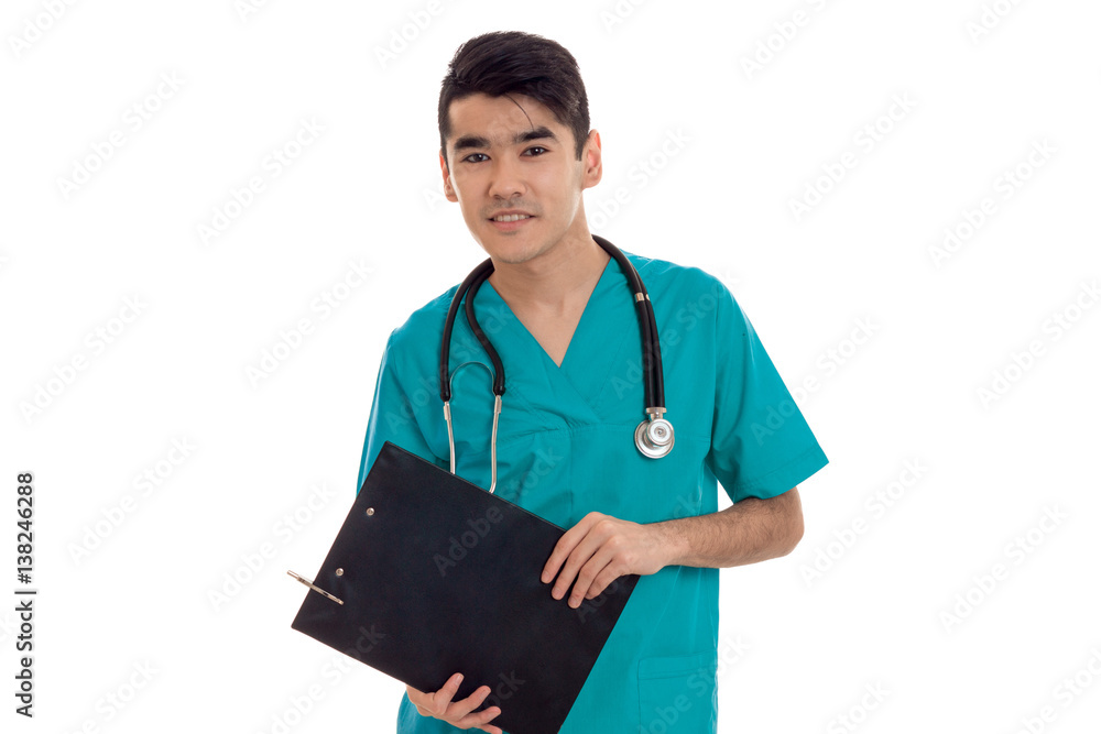 young pretty brunette male doctor in uniform with stethoscope make notes and looking at the camera isolated on white background young pretty brunette male doctor in uniform with stethoscope make notes and looking at the camera isolated on white background