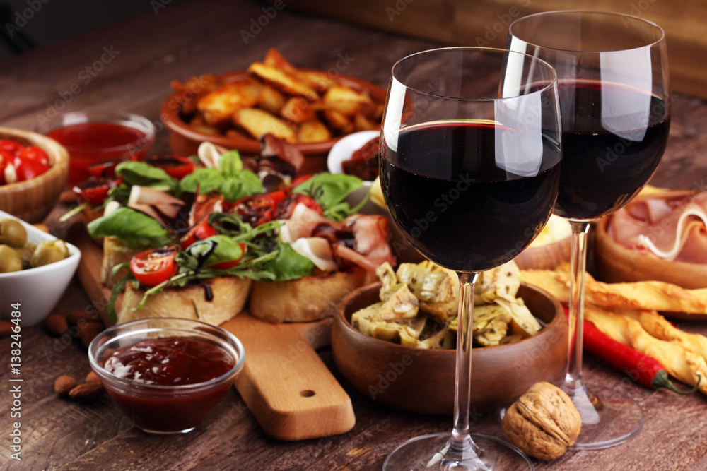 Fototapeta Zestaw przekąsek włoskich antipasti. Odmiana serowa, oliwki śródziemnomorskie, marynaty, szynka parmeńska, pomidory, karczochy i wino w szklankach