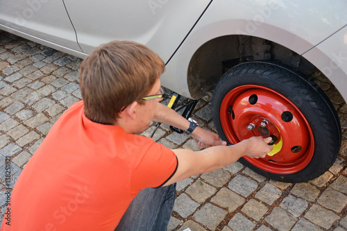 Replacing the tires on the car. Flat tire. Attaching a spare wheel. Lifting the car on the jack. Accident with punctured tires. Hard man work.