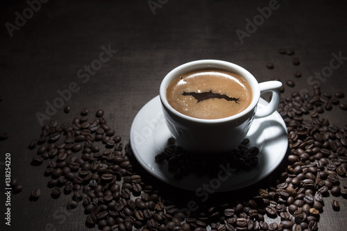 Cup of coffee with grains on wooden table on dark background © photovlada78