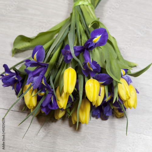 Fototapeta Naklejka Na Ścianę i Meble -  bouquet of yellow tulips and blue irises lying on the floor