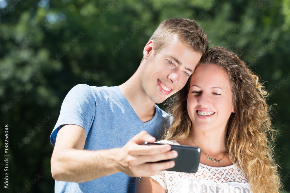 young couple taking selfie photo in a park in summer