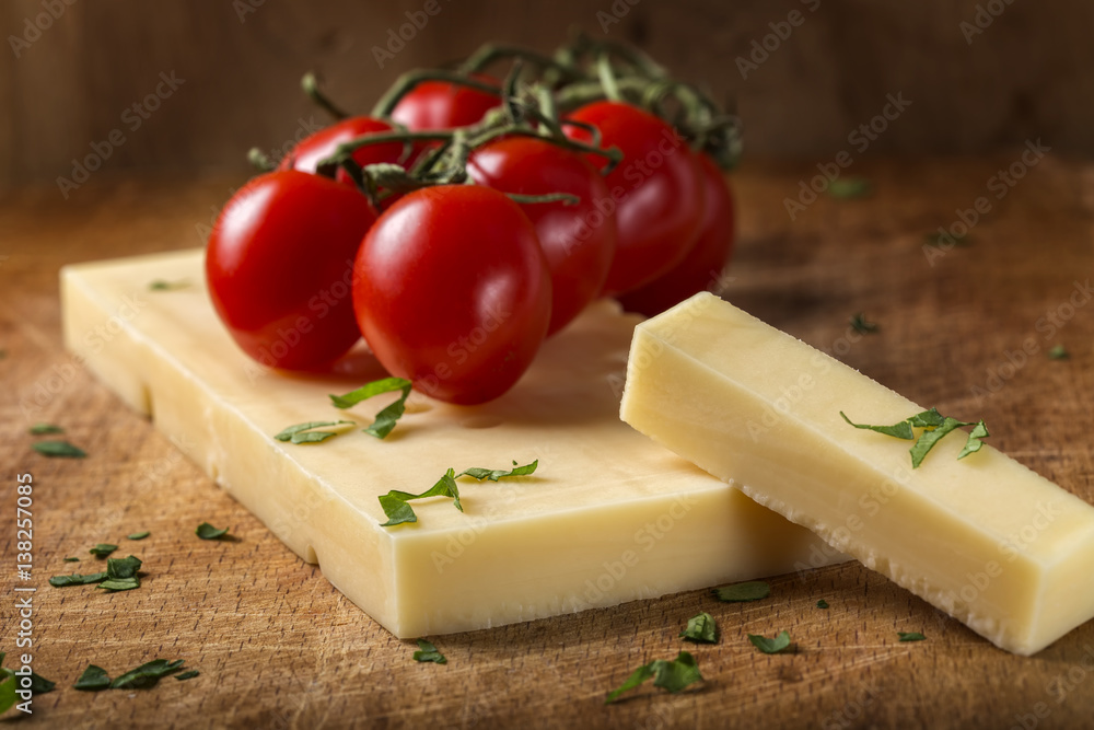 Emmental cheese with cherry tomatoes and herbs on wood Emmental cheese with cherry tomatoes and herbs on wood
