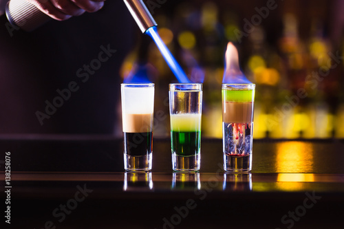 Three multi-layer burning cocktail. The bartender ignites them lighter. photo