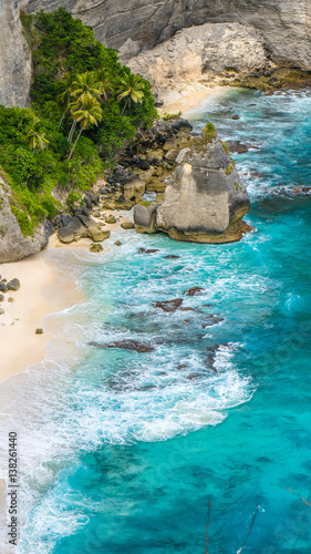 Rock in the ocean with beautiful palms behind at Atuh beach on Nusa Penida island, Indonesia © Igor Tichonow