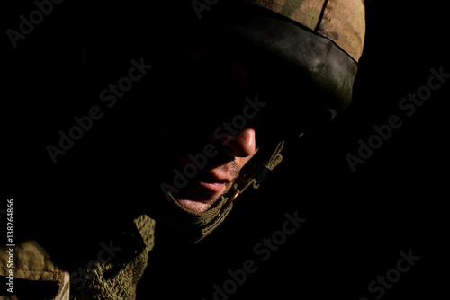 Portrait of soldier with half face in deep shadow.