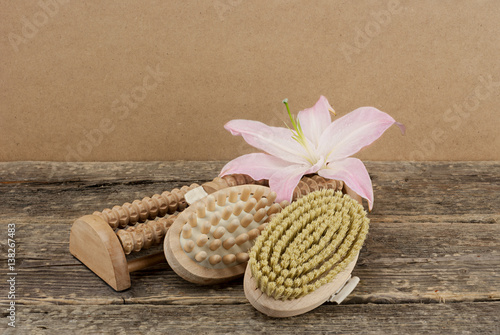 Beautiful composition with pink lily and massage brushes on wooden background, skin and body care concept photo