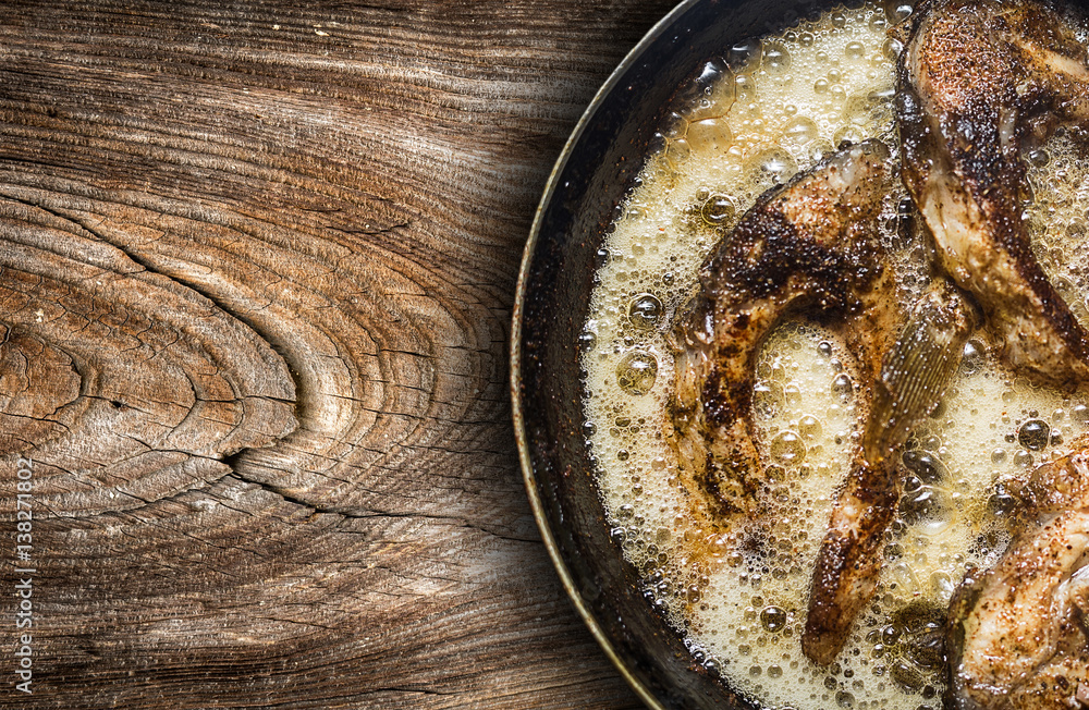 Fish in a frying pan. horizontal view from above. On the wood Fish in a frying pan. horizontal view from above. On the wood