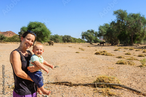 Mutter mit Säugling betrachtet Elefanten (Loxodonta africana) im Aba Huab Trockenflussbett
