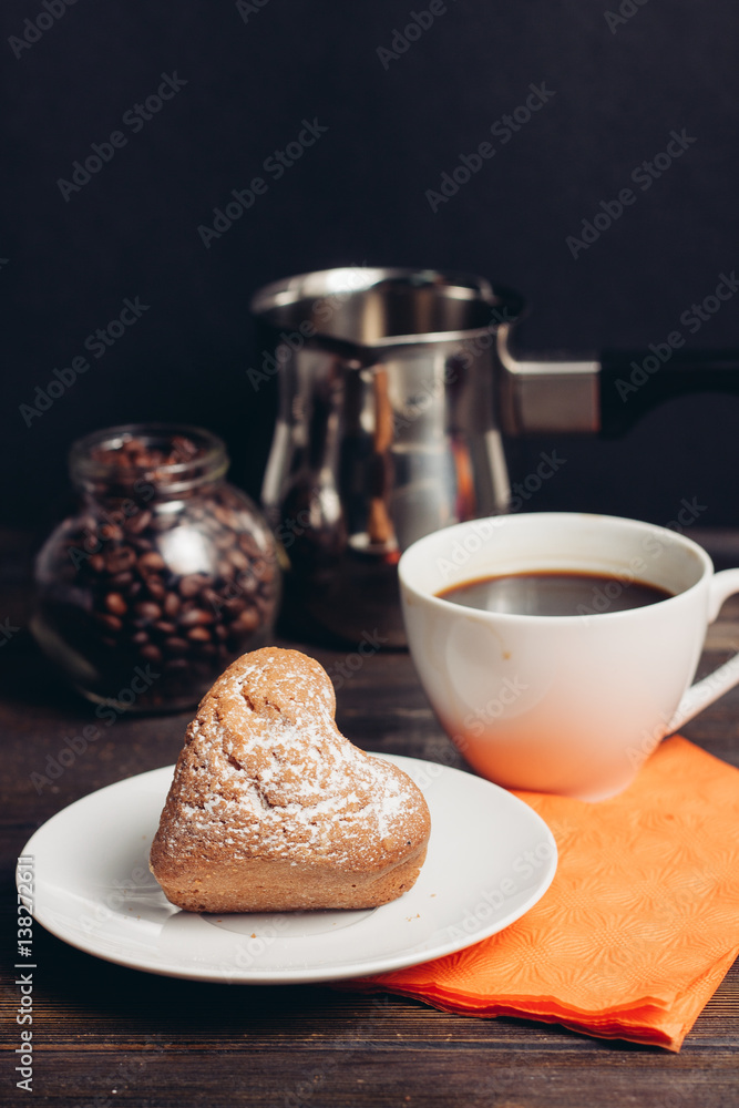 a white cup with a drink and a cupcake on a plate, a ladle and a jar with coffee beans a white cup with a drink and a cupcake on a plate, a ladle and a jar with coffee beans