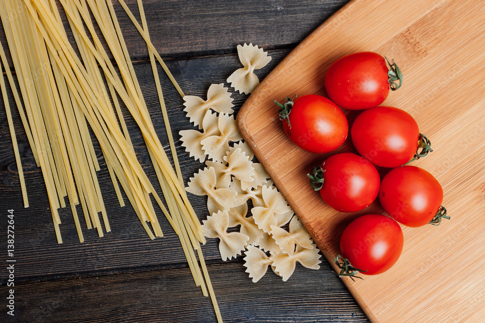 red tomatoes lie on a board and spaghetti with noodles on a table red tomatoes lie on a board and spaghetti with noodles on a table