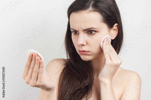 a dark-haired woman examines a cotton pad in her hand