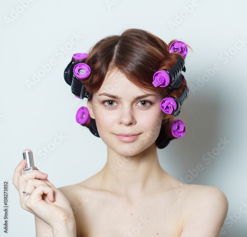 woman with purple curlers and lipstick in her hand