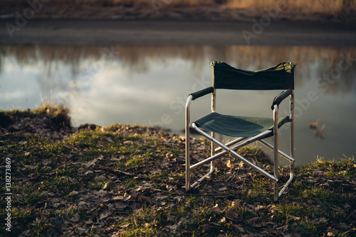 a folding chair on the grass and a river in the background