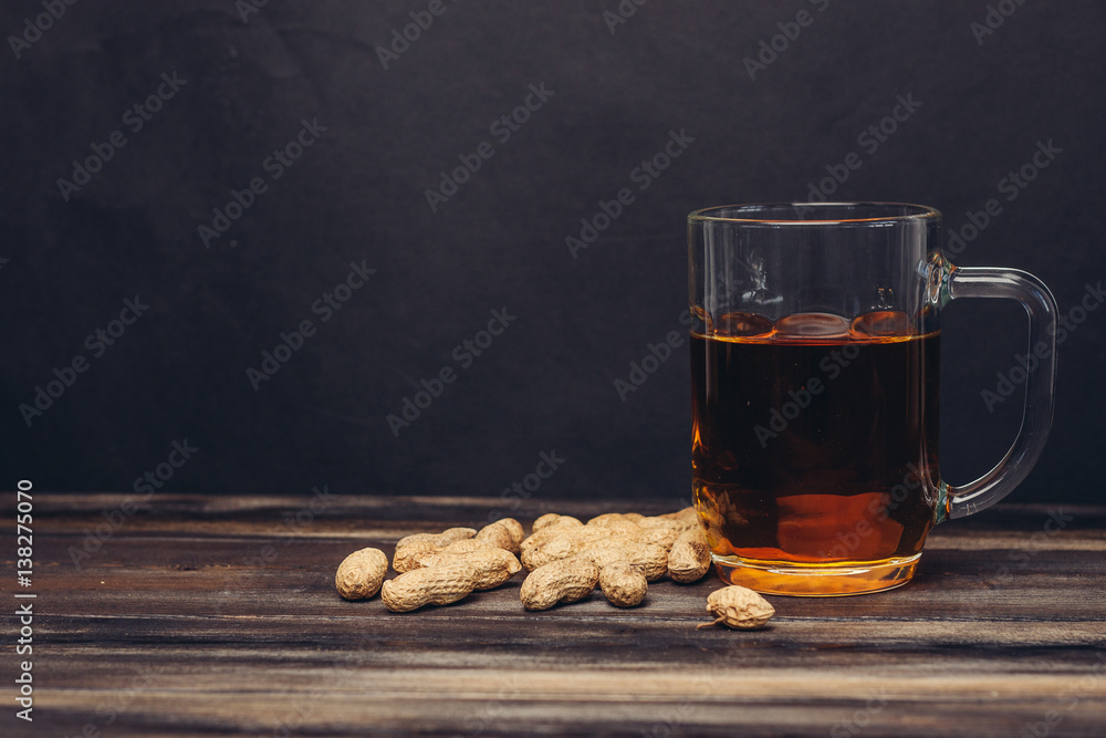 cup of tea on a wooden table with spilled peanuts