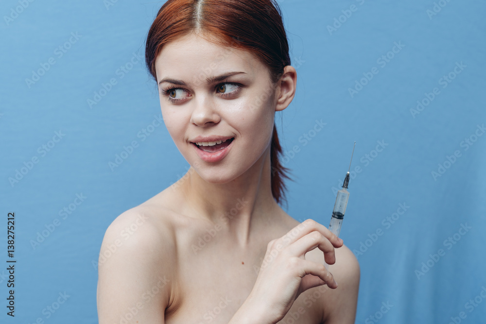 red-haired woman holding a syringe in her hand red-haired woman holding a syringe in her hand